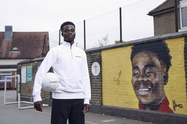 Bukayo stands in front of his mural at his old school 