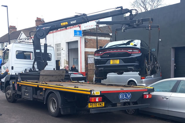 Car being towed on a truck during the daytime parking enforcement operation in Hanger Hill